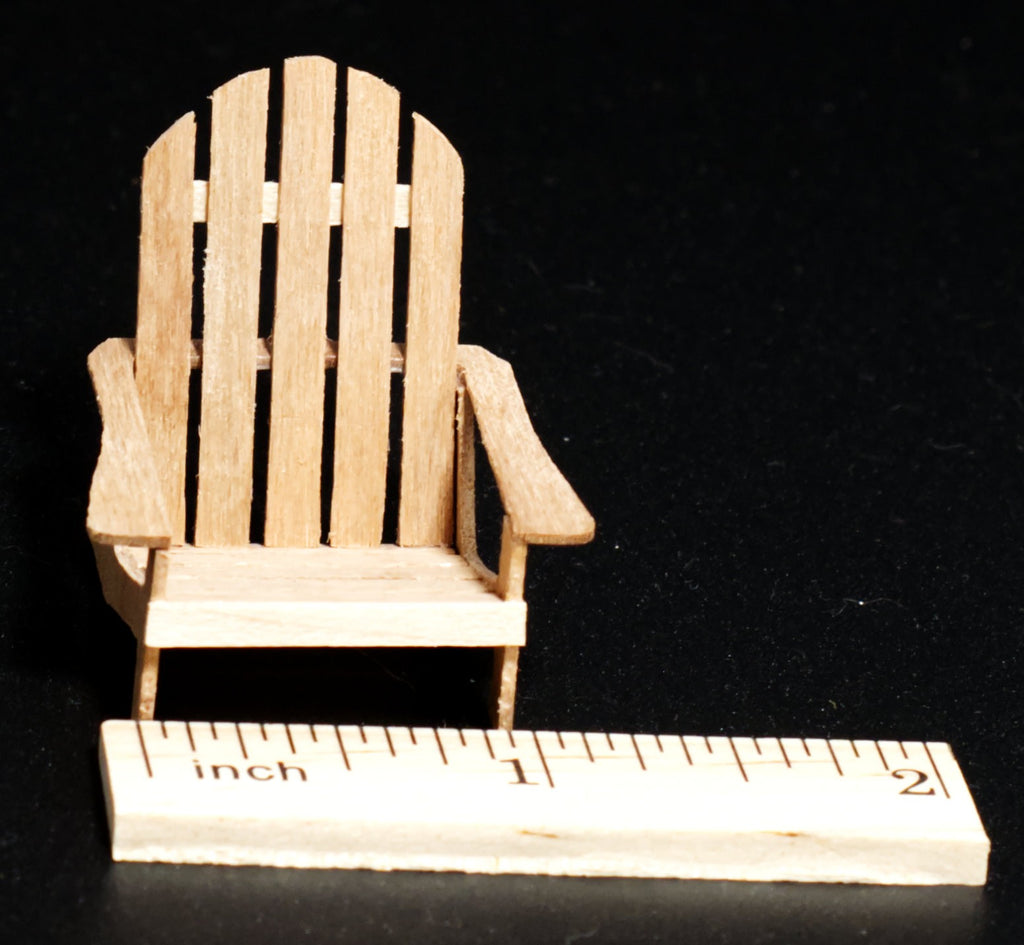 A 1:24 scale  light wood Adirondack chair shown next to a small wooden ruler marked in inches, set against a solid black background.