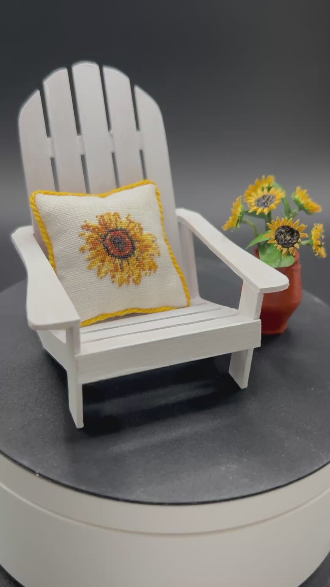 Video of an Adirondack chair with a sunflower pillow and a vase of sunflowers next to it